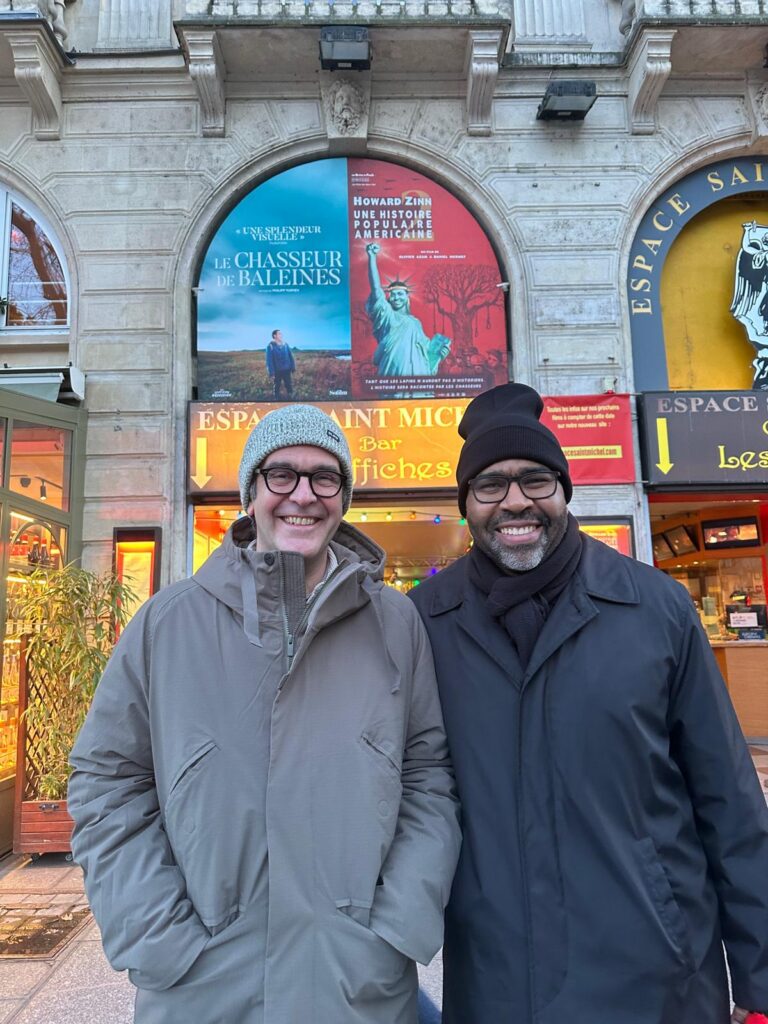 2 people in winter hats and coats standing in front of movie theater