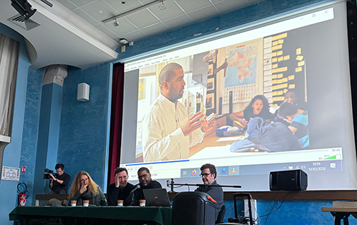 4 people sitting at a table with a screen behind then